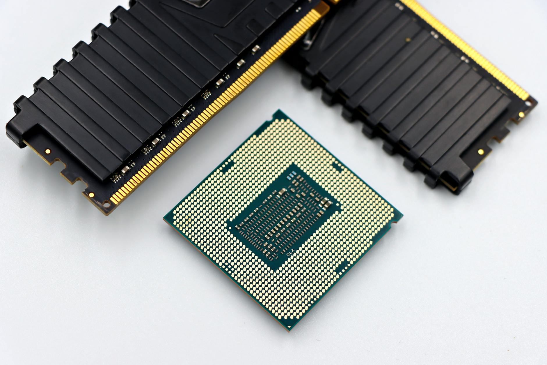 A CPU and RAM sticks displayed on a white surface, showcasing computer hardware components.
